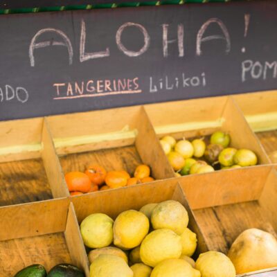 Colorful variety of tropical fruits including tangerines and lilikoi at a local market stand.