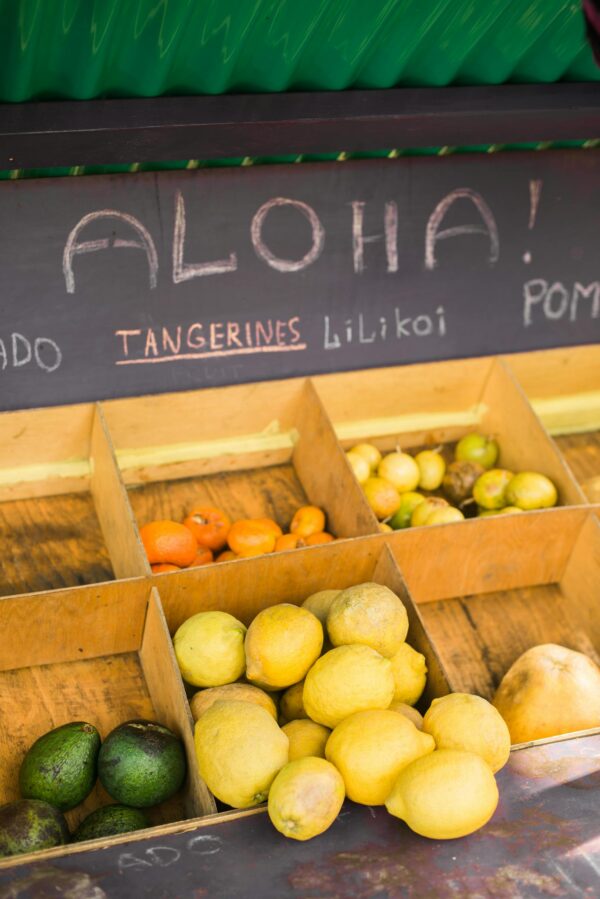 Colorful variety of tropical fruits including tangerines and lilikoi at a local market stand.