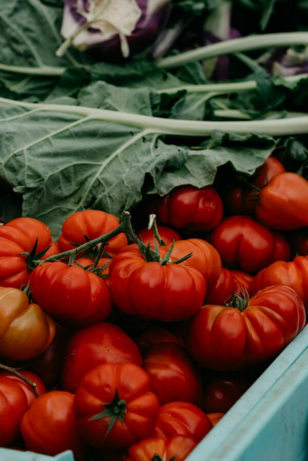 Ripe red tomatoes with leafy greens in a market setting, capturing organic freshness.