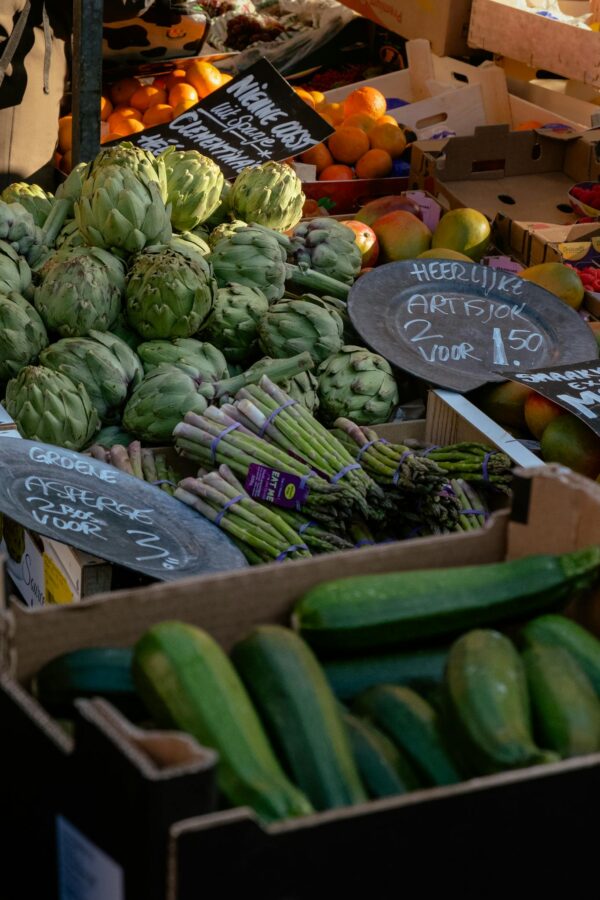 Vibrant display of fresh organic vegetables at an outdoor farmers market showcasing artichokes, zucchini, and asparagus.