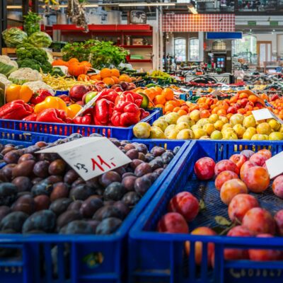 Vibrant fruits and vegetables displayed in crates at an indoor market in Wrocław, Poland.