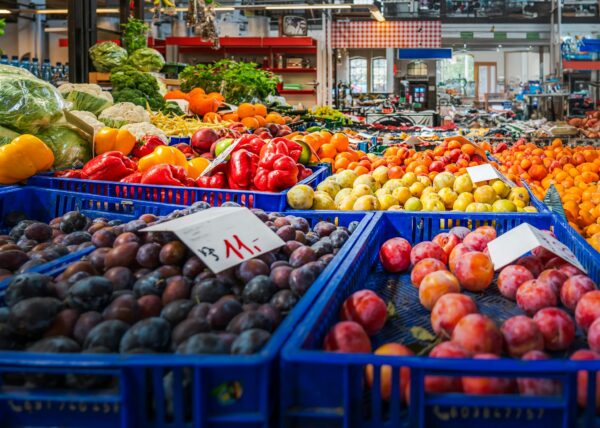 Vibrant fruits and vegetables displayed in crates at an indoor market in Wrocław, Poland.